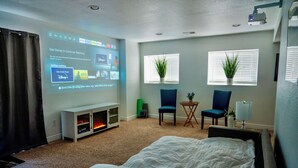 A hotel room with a bed, a TV, a small table with chairs, and two potted plants. - Private Entrance\Modern&Cozy Central Bliss\King Villa\55" 4k Roku\Full Kitchen (Colorado Springs)