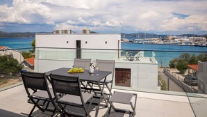 Eine Terrasse mit Tisch und Stühlen mit Blick auf einen Yachthafen und Boote.