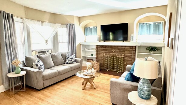 A living room with a sofa, a coffee table, a TV, and a fireplace. - Farmhouse In The City CLE Clinic-Long Stays Welcome - 2bd/1bth WiFi, Full Kitch (Shaker Heights)