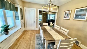 A dining area with a wooden table, white chairs, a vase with flowers, and a chandelier. - Farmhouse In The City CLE Clinic-Long Stays Welcome - 2bd/1bth WiFi, Full Kitch (Shaker Heights)