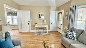 A living room with a white desk, two sofas, a coffee table, and a mirror on the wall. - Farmhouse In The City CLE Clinic-Long Stays Welcome - 2bd/1bth WiFi, Full Kitch (Shaker Heights)