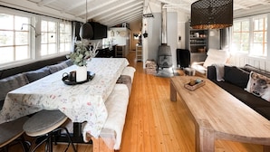 Un vaste espace de vie comprenant une grande table à manger en bois, un coin salon confortable et une cheminée.