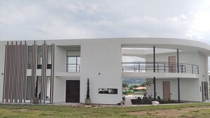 Un edificio moderno de dos pisos con techo plano, ventanas grandes y un balcón.