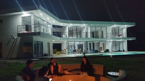 Una casa moderna de dos plantas con un amplio patio exterior que incluye un pozo de fuego.