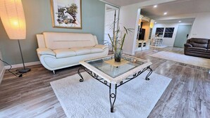 A modern living room with a white sofa, a glass-top coffee table, and a decorative plant. - MANATEE MANOR, Swim with Manatees! 3bdrm 2 bth home Crystal River with PET Bdrm! (Crystal River)