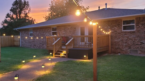 Une maison en briques avec une terrasse en bois et un éclairage extérieur.