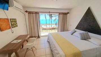Une chambre d’hôtel avec un lit, un bureau, une chaise et une vue sur la plage.