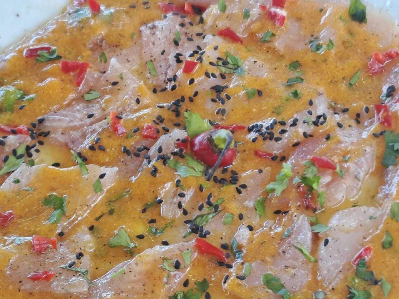 Un plato con camarones, pimientos rojos y semillas de sésamo negro.