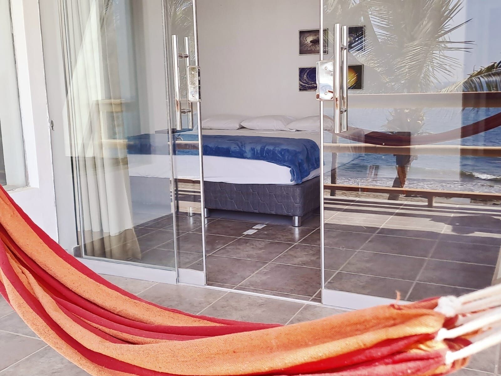 Een kamer met een bed, een hangmat en een glazen deur die uitkomt op een balkon.