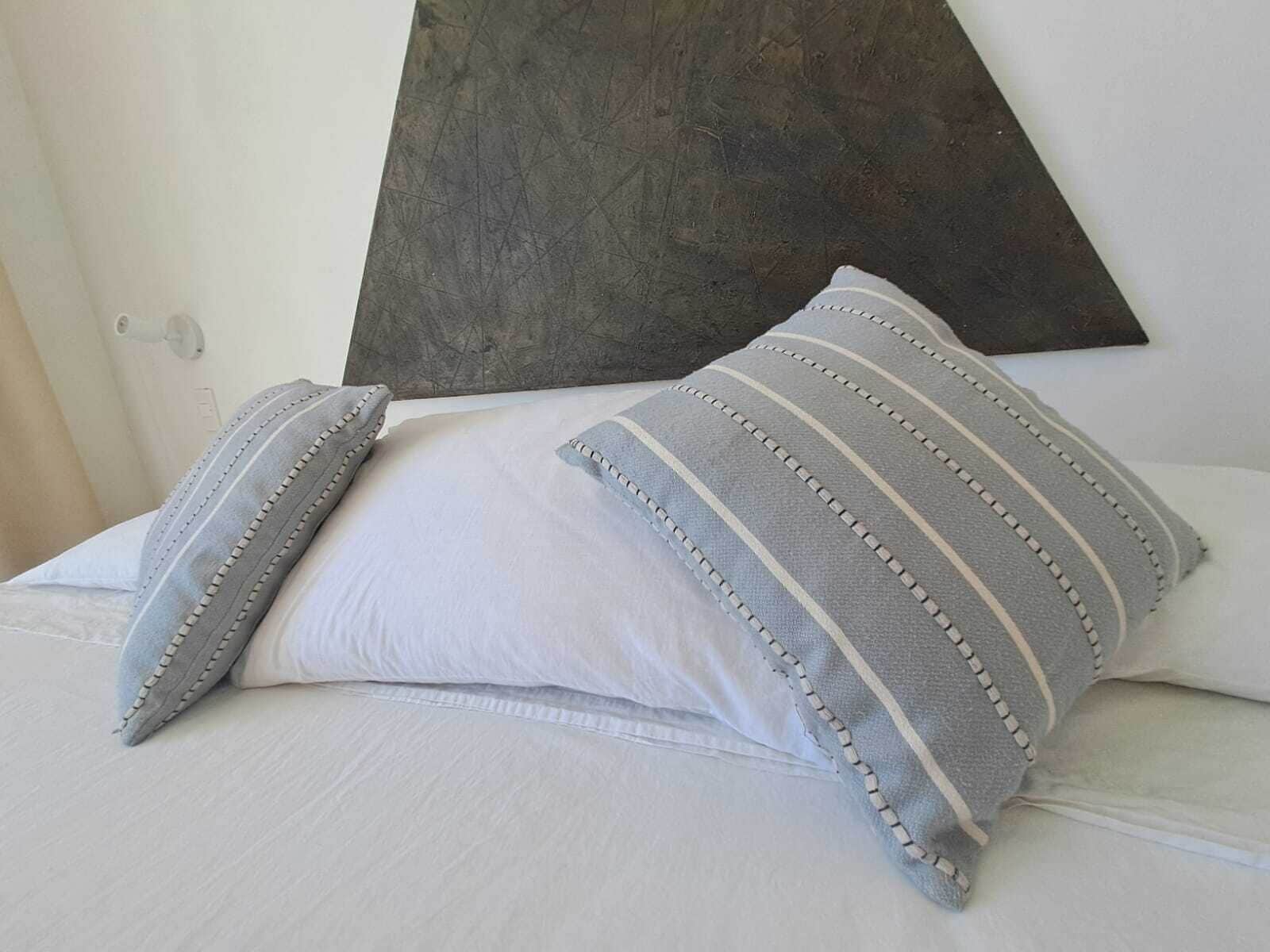 A bed with white bedding and striped pillows.