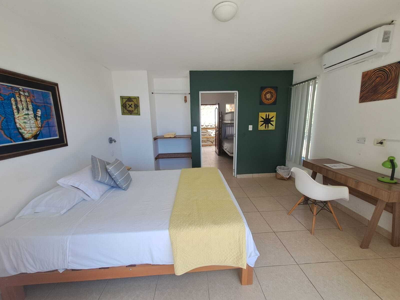 Un dormitorio con una cama, un escritorio y una silla. Hay una puerta que da al baño.