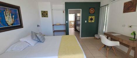 Un dormitorio con una cama, un escritorio y una silla. Hay una puerta que da al baño.