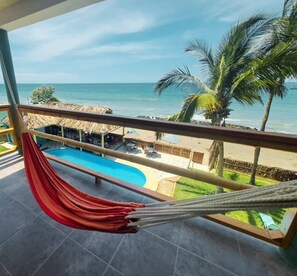 A balcony with a hammock, a pool, and a view of the beach and ocean. - Hotelier Home (Máncora)