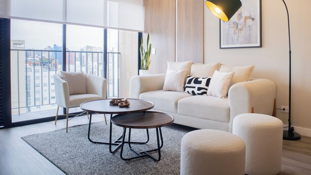 Una sala de estar moderna con un sofá, dos sillones, una mesa de centro y una lámpara de pie.