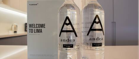 Two water bottles with 'andea' branding on a counter, a 'WELCOME TO LIMA' sign, and a modern interior.