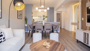Una sala de estar moderna con comedor, una mesa de centro de madera y un televisor sobre un mueble bajo.