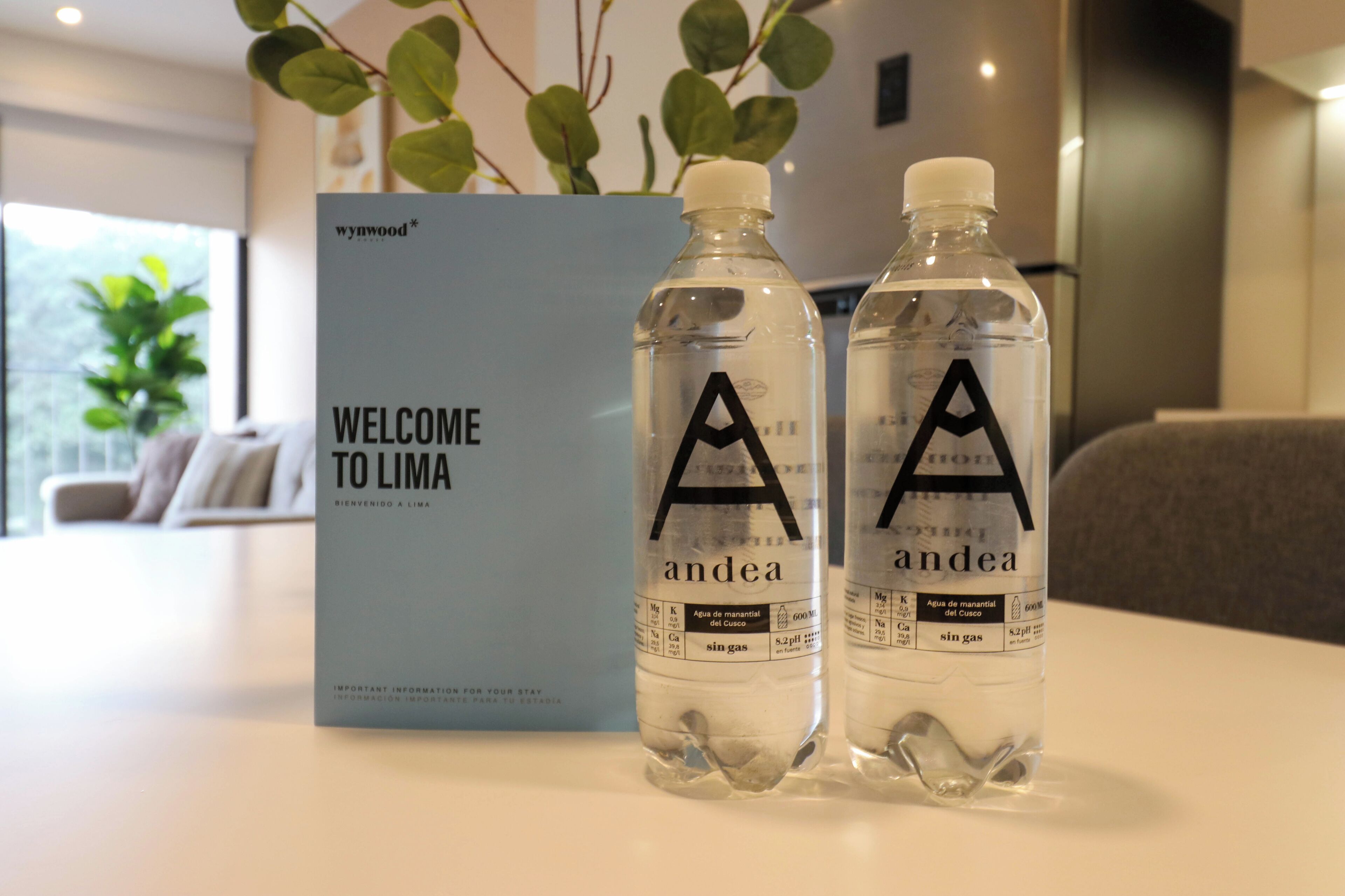 Deux bouteilles d’eau étiquetées « A » et « andea », avec un panneau d’accueil en arrière-plan.