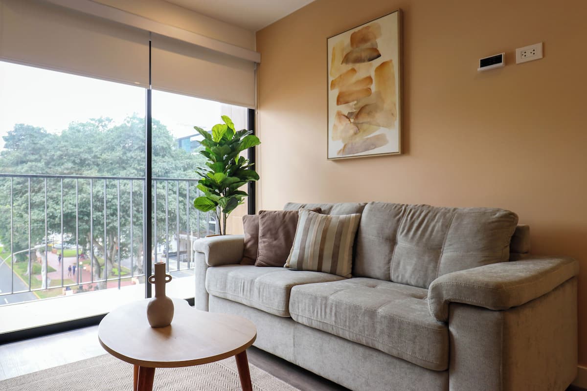 A living room with a sofa, a small round table, and a potted plant.