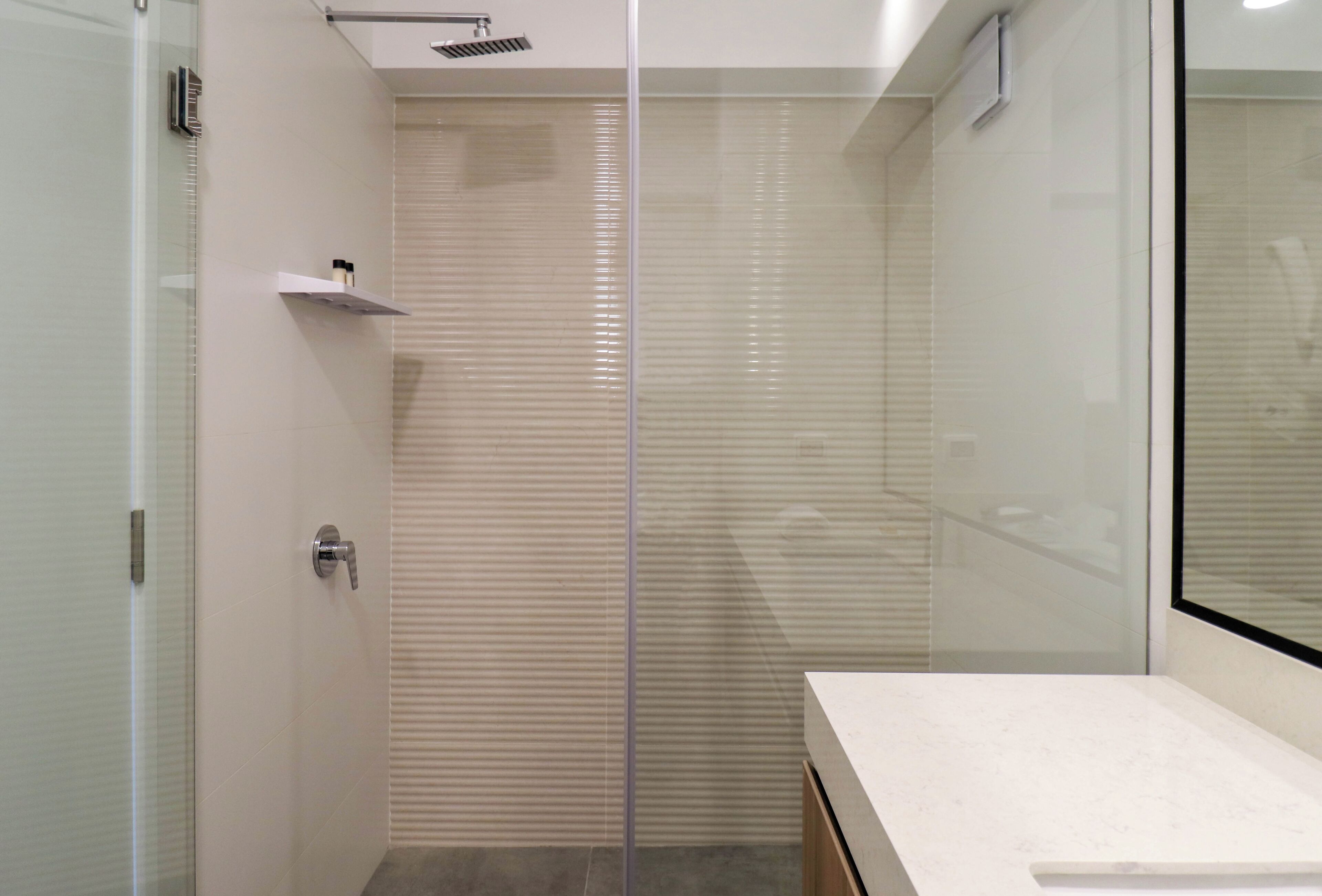 Ein modernes Badezimmer mit Duschkabine aus Glas, einer weißen Arbeitsplatte und einer Tür aus mattiertem Glas.