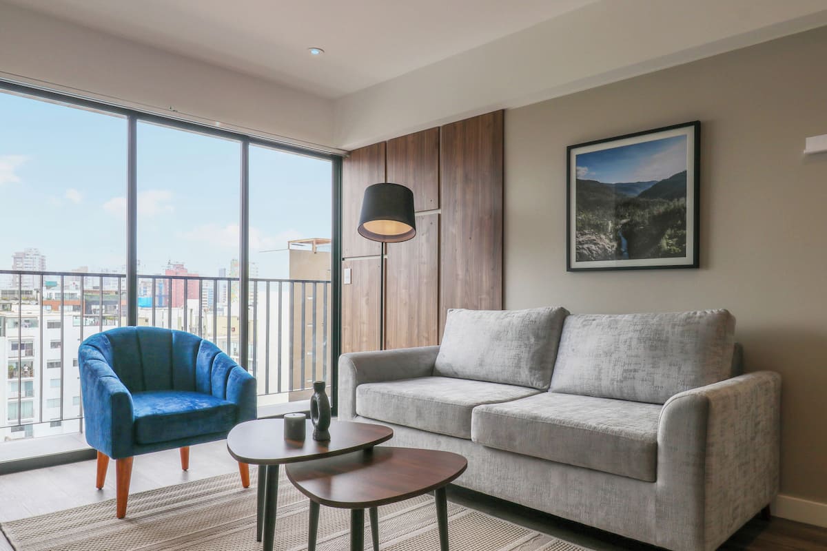 A modern living room with a grey sofa, a blue armchair, and a small table.