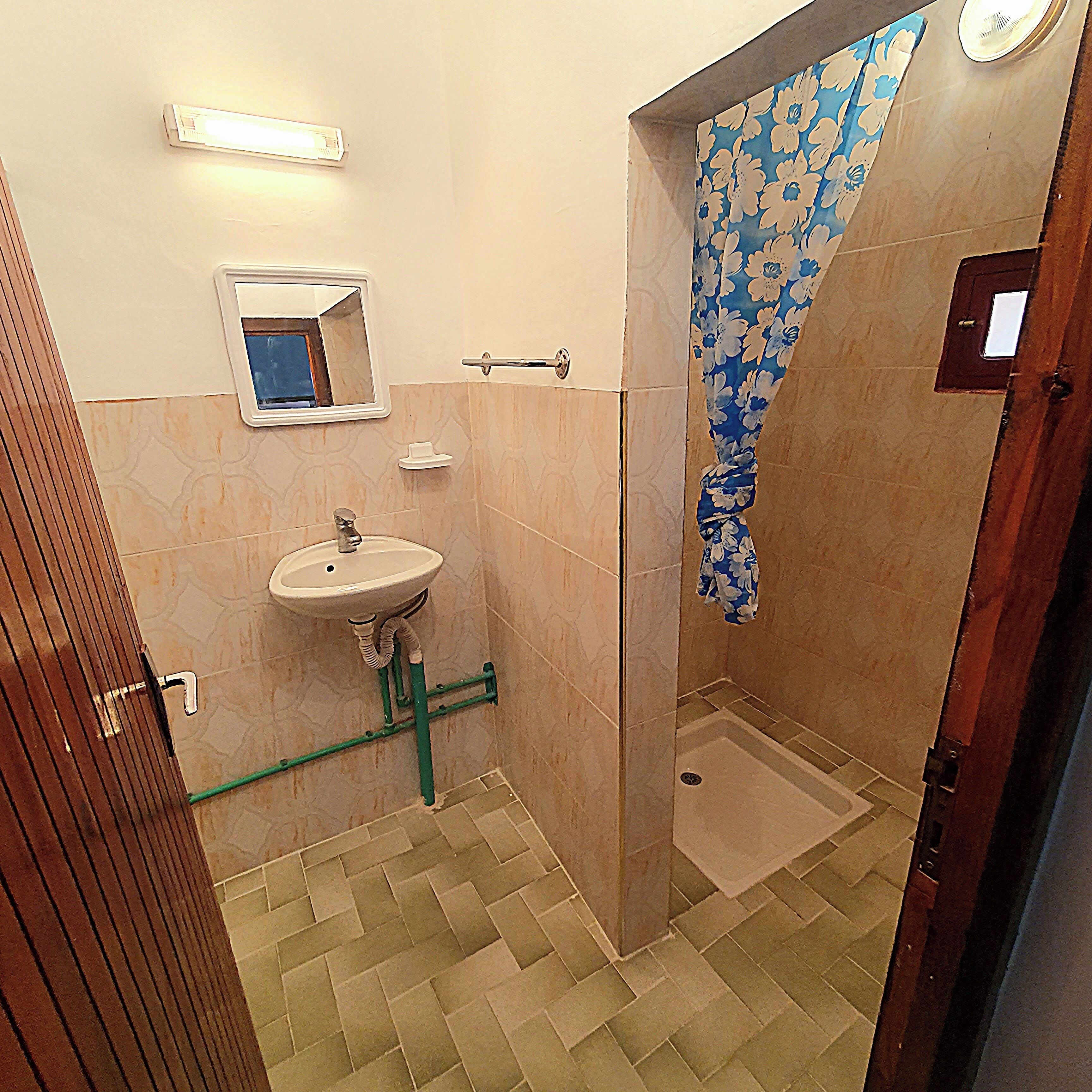 Ein Badezimmer mit Waschbecken, Spiegel, Duschvorhang und Fliesenboden.