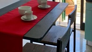 En matplats med ett bord dukat för två personer, en röd duk och utsikt över en byggnad genom en öppen dörr.