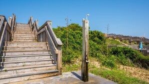 Eine Holztreppe führt zu einer Terrasse mit einer Metallkonstruktion auf der rechten Seite.