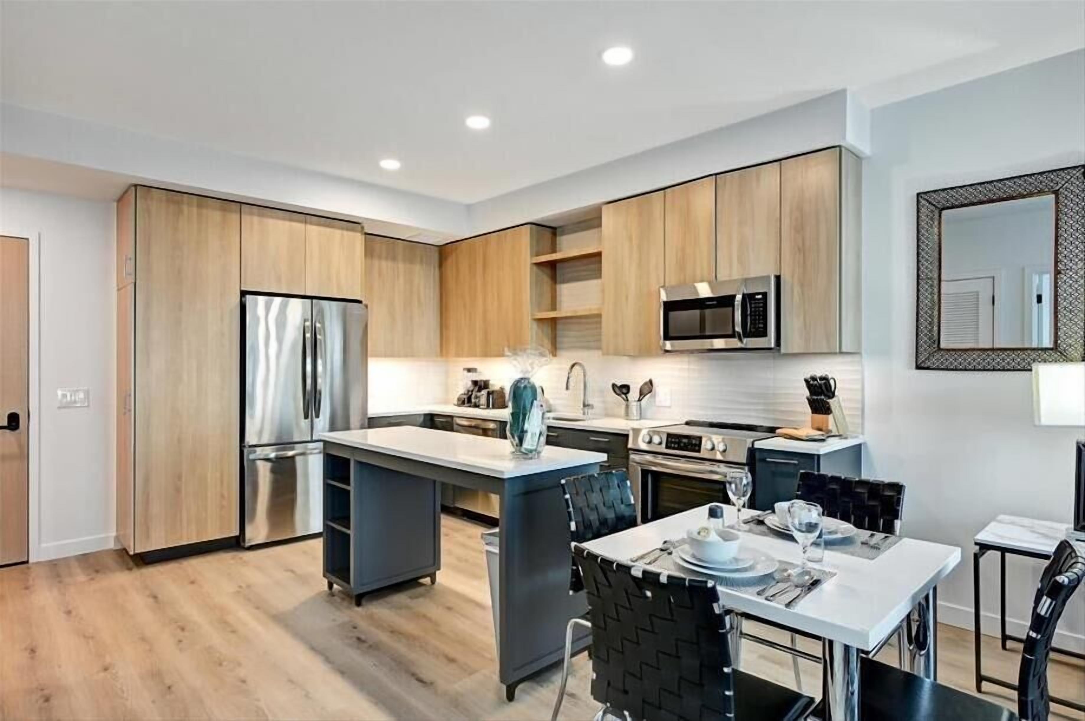 Una cocina moderna con armarios de madera, electrodomésticos de acero inoxidable y una isla central.