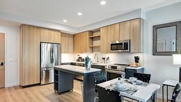 Una cocina moderna con armarios de madera, electrodomésticos de acero inoxidable y una isla central.