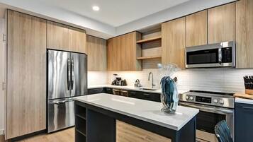 A modern kitchen with wooden cabinets, stainless steel appliances, and a marble countertop.