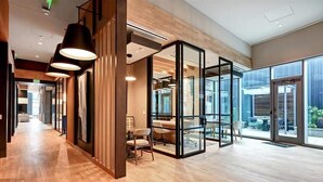 Un interior moderno con piso de madera, divisiones de vidrio y una zona de comedor con sillas.