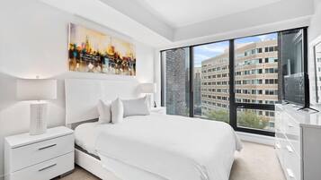 Ein modernes Hotelzimmer mit einem großen Bett, einem Nachttisch, einer Kommode und einem Stadtbild an der Wand.