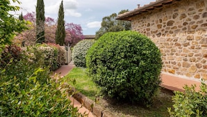 A stone building with a tiled roof, surrounded by well-maintained gardens and trees. - Cosy apartment in villa with WIFI, hot tub, private pool, TV, patio, pets allowed and panoramic ... (Manciano)