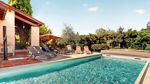 A swimming pool with lounge chairs and a covered seating area. - Beautiful home in Meyzieu (Meyzieu)