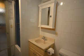 Un baño con un lavamanos color beige, un espejo y un inodoro.