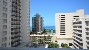 Un hotel moderno de gran altura con múltiples balcones, una zona de piscina con tumbonas y vistas al océano.
