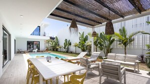 A modern outdoor patio with a pool, seating, and tropical plants. - Villa Glamour / Villa with pool (Aroeira)