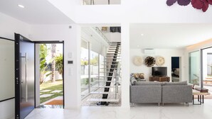 A modern interior with a staircase leading to a balcony, a grey sofa, and a flat-screen TV. - Villa Glamour / Villa with pool (Aroeira)