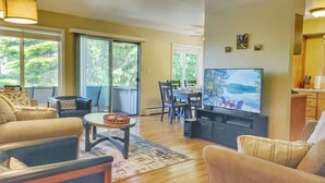 A living room with a TV, sofa, chairs, and a dining table. - Waterfront Condo AC Boat Slip Downtown  (Sandpoint)