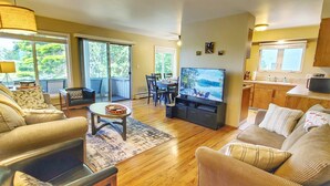 A living room with a TV, sofa, and dining area. - Waterfront Condo AC Boat Slip Downtown  (Sandpoint)