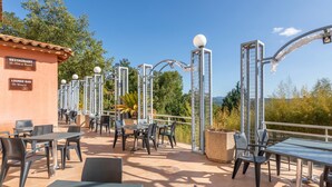 Un'area patio esterna con tavoli, sedie, un bar lounge e attrezzature per esercizi.