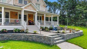A two-story house with a covered porch, stone steps, and a well-maintained garden. - Coastal Escape: Steps to Red River Beach (Harwich Port)