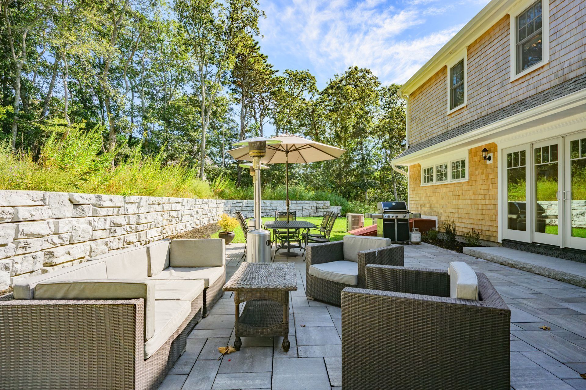 An outdoor patio with wicker furniture, a table, and an umbrella.