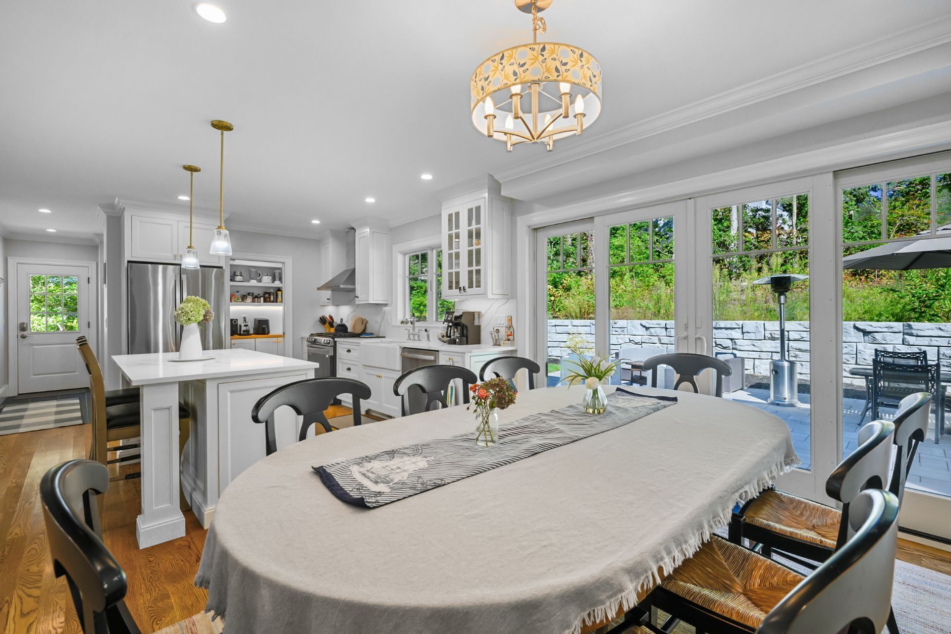 A modern kitchen with white cabinetry, a central island, and a dining area with a table and chairs.