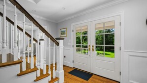 A staircase with white balusters and wooden steps leading to a white door with glass panels. - Coastal Escape: Steps to Red River Beach (Harwich Port)