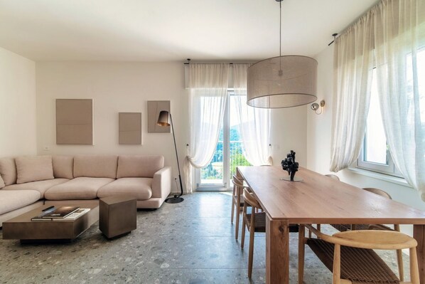 A modern living room with a sofa, a dining table, and a lamp.