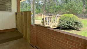 Eine überdachte Veranda mit Backsteinmauer und Holzterrasse.