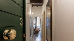 A hallway with a green door marked with the number 3, a wooden chair, and a framed artwork on the wall.
