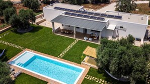 A modern house with a swimming pool, solar panels, and a well-maintained garden.