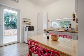 A modern kitchen with a dining table, chairs, a microwave, and a window.